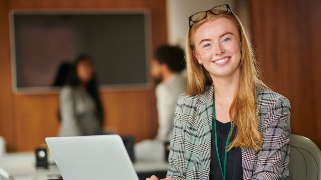 A confident professional working at a desk in a bright modern UK office on a Skilled Worker visa.