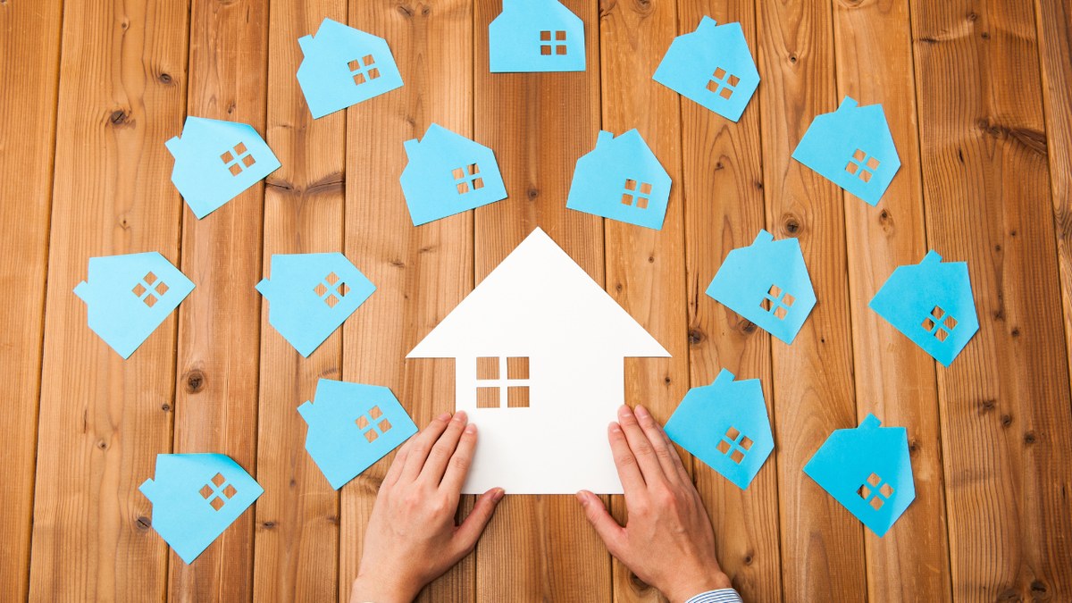 Can I Include More Than One Property in My Indian Power of Attorney? Hands around a paper house surrounded by smaller blue houses, representing one Indian Power of Attorney covering several properties
