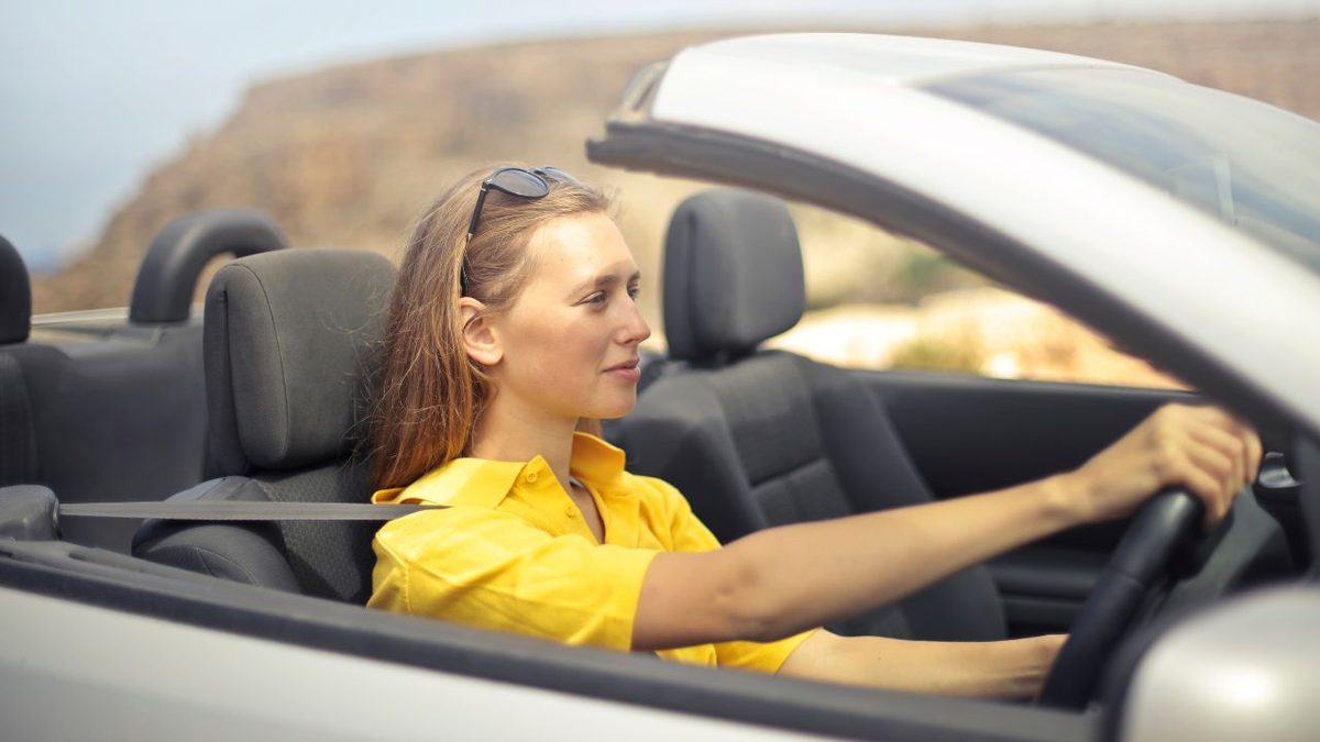 Driving Offences and British Citizenship Applications Woman driving a convertible car on an open road, illustrating how driving offences are treated in British citizenship applications