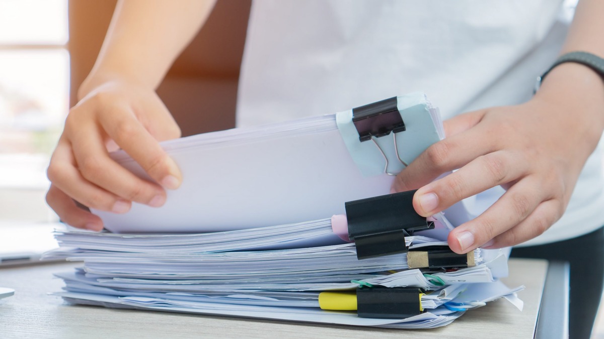 FLR M supporting documents 2021 Hands organising a thick stack of clipped papers on a desk, preparing the supporting documents for an FLR(M) spouse visa extension