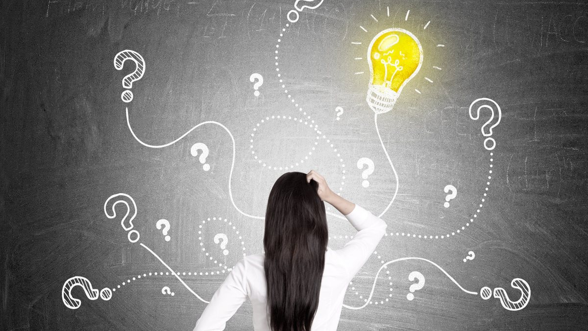 Top Questions Indian NRI Power of Attorney Woman facing a chalkboard of question marks and a lit bulb, illustrating common questions NRIs ask about an Indian Power of Attorney