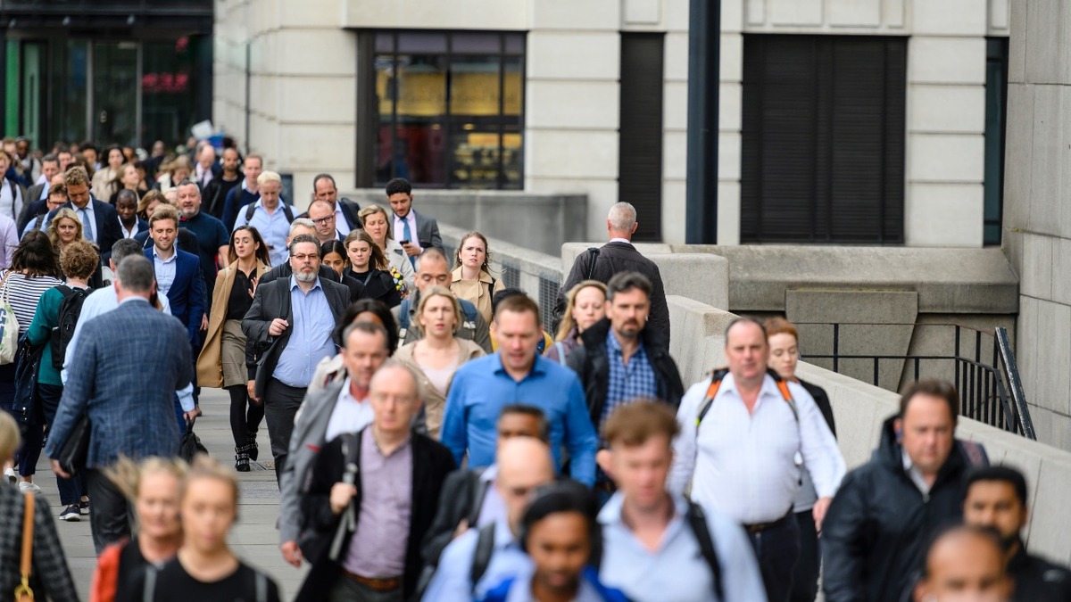 eVisa Busy crowd of commuters walking through central London, illustrating eVisas as online proof of UK immigration status