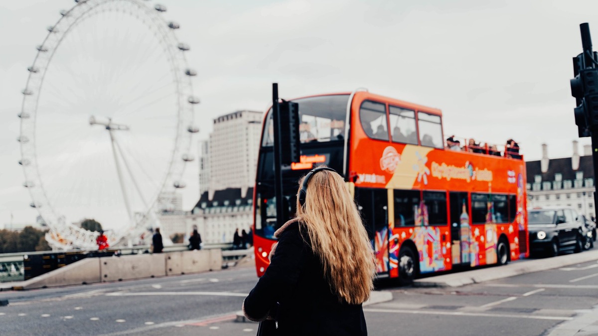 UK Visitor Visa Application Mistakes Tourist looking at the London Eye and a red sightseeing bus, illustrating common mistakes in UK visitor visa applications
